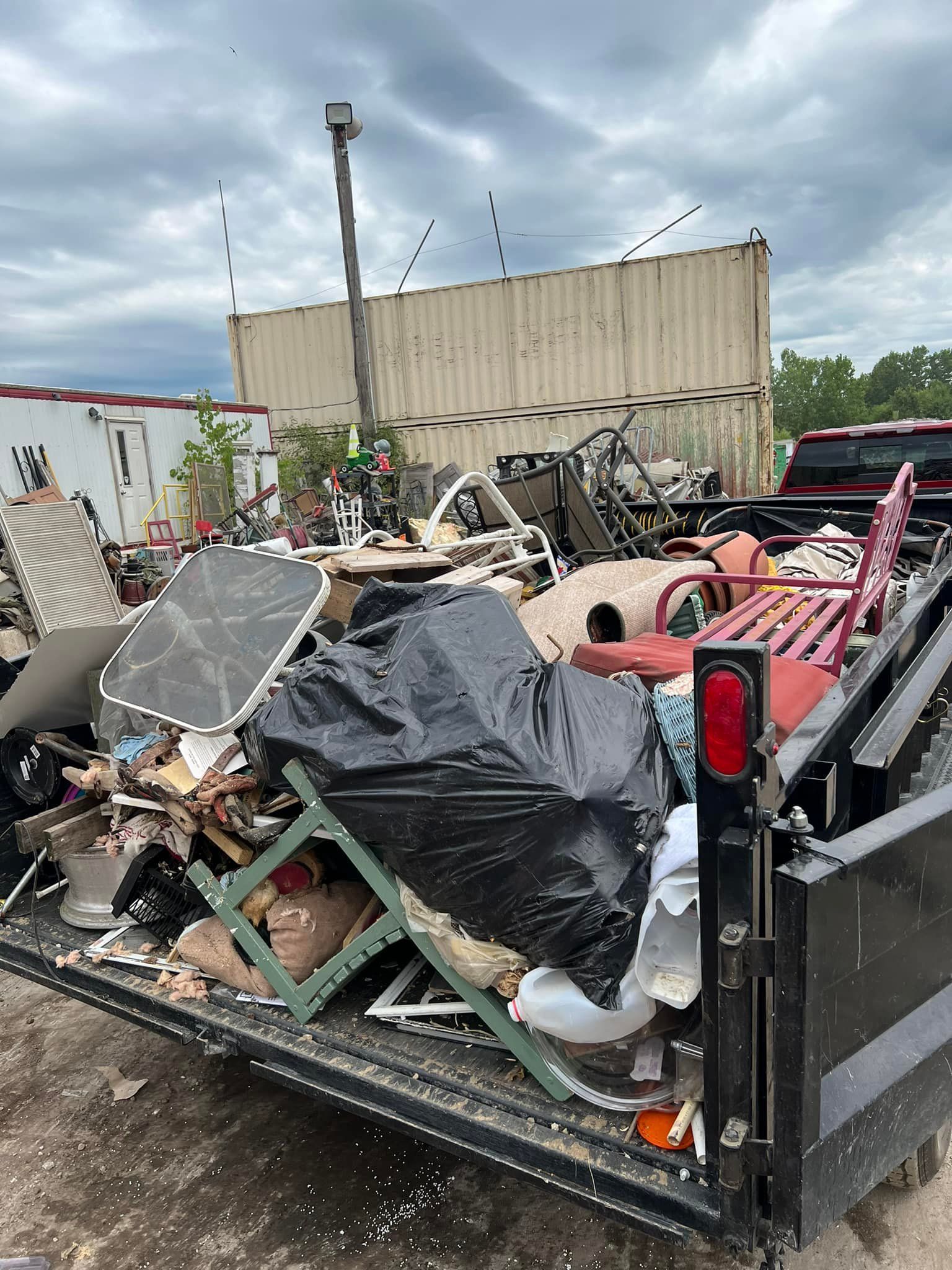 A dumpster filled with junk is parked in front of a building.