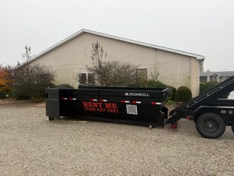 A black dumpster labeled 