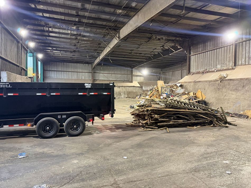 A dump trailer is parked in front of a house.