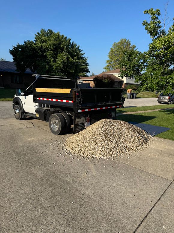A dumpster trailer is parked in a parking lot in front of a brick building.