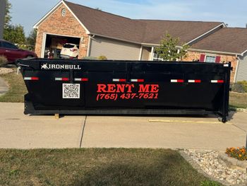A dumpster is sitting on top of a pile of wood.