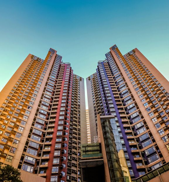 Two colorful high-rise apartment towers viewed from below against a blue sky