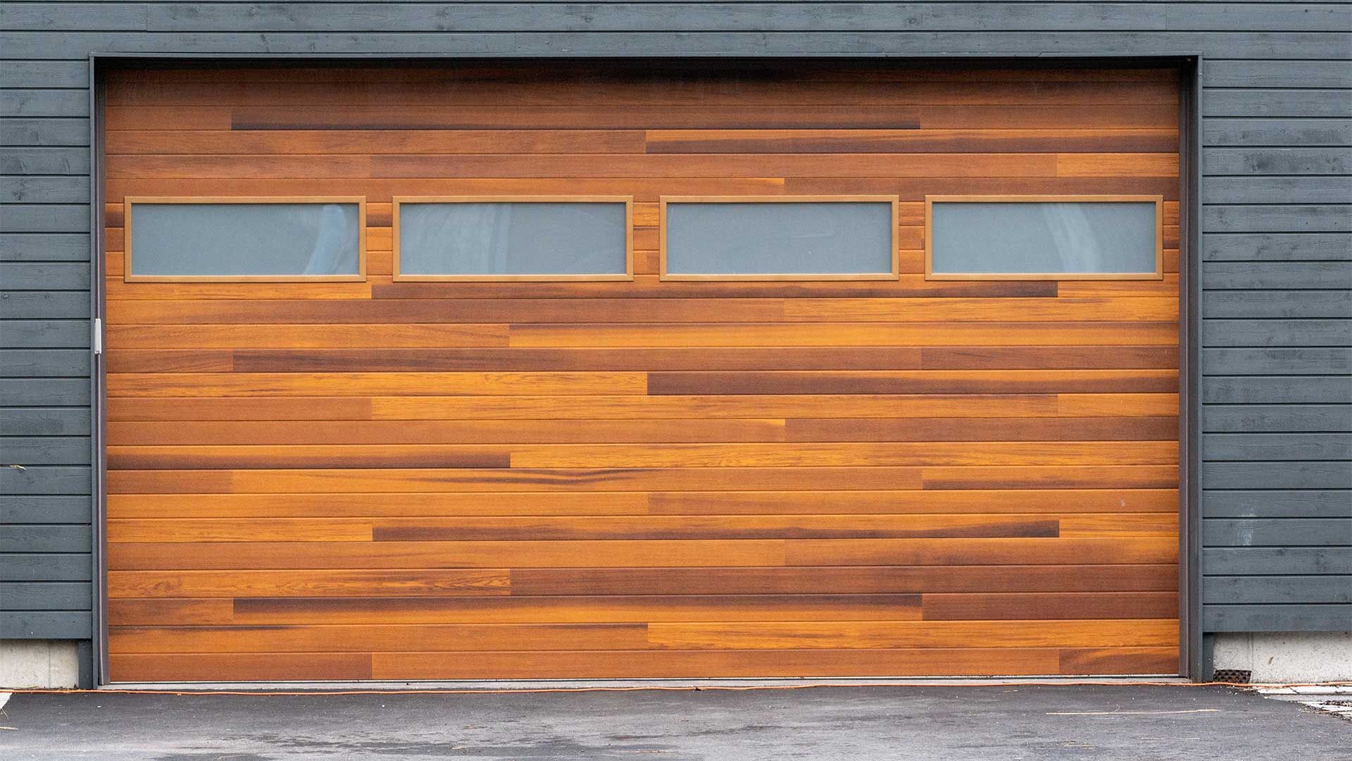 A wooden garage door with square windows on a black building.