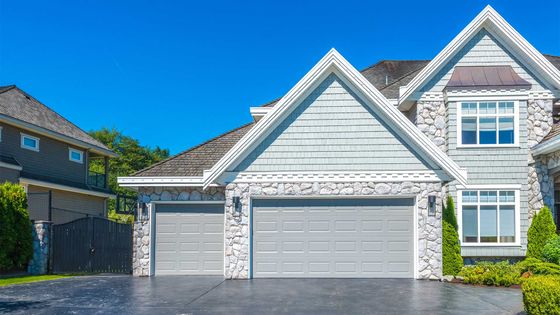 A large house with two garage doors and a driveway.