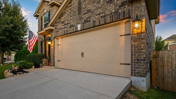 A large brick house with a large garage door and an american flag in front of it.
