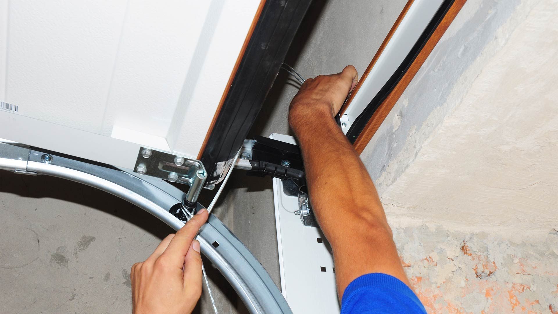 A man is fixing a garage door with a wrench.