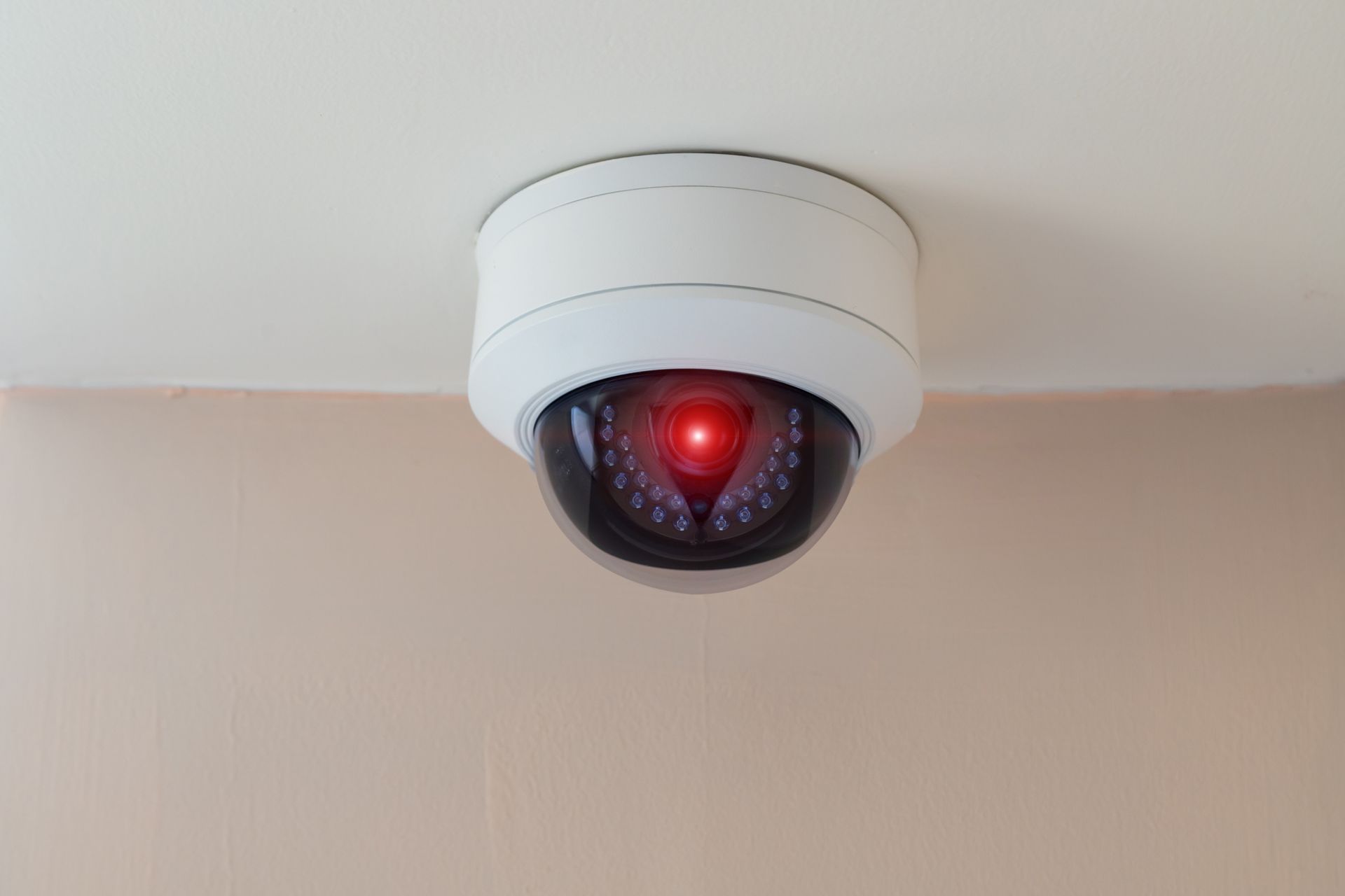 Telecamera di sicurezza montata su un soffitto bianco con una luce rossa.