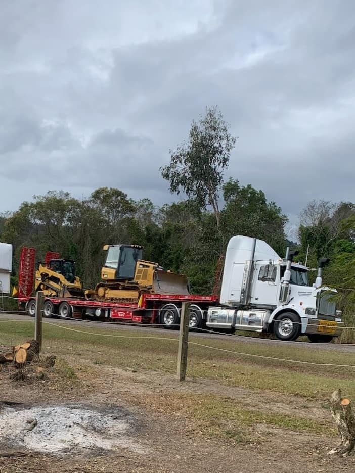 A Semi Truck Is Carrying A Bulldozer On A Flatbed Trailer — Equiptranz In Kybong, QLD