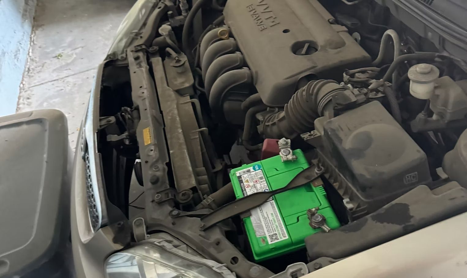 Car engine bay with green battery.