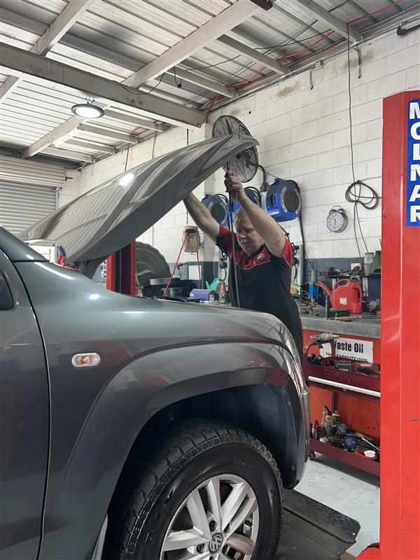 A Man is Working on a Car Engine With a Laptop — Pelican Motors Service Centre In Caloundra West, QLD 