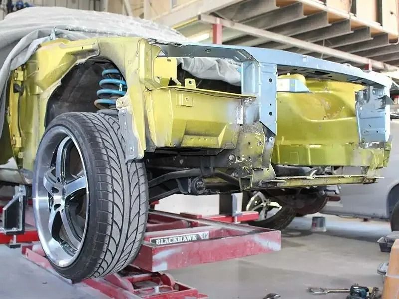 A Yellow Car is Sitting on a Lift in a Garage — Pelican Motors - Repco Authorised Car Service Caloundra In Caloundra, West