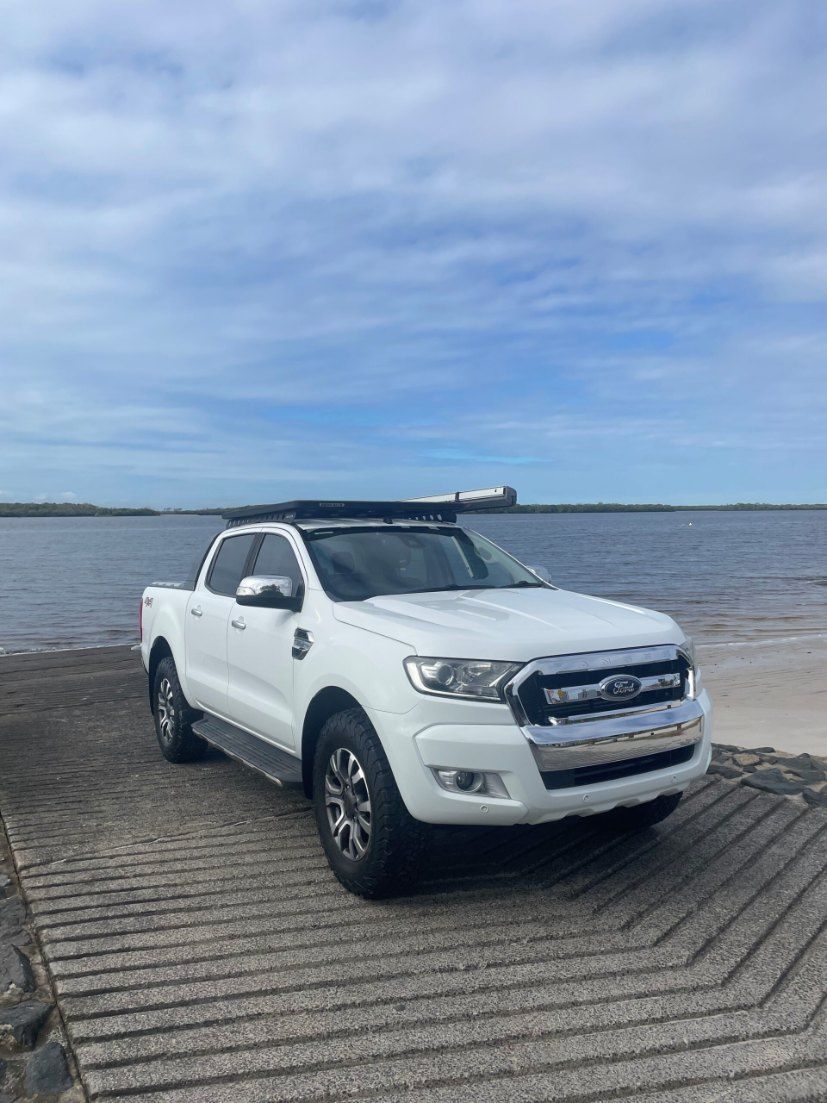 A White Ford Ranger is Parked on a Dock Next to a Body of Water β Pelican Motors Service Centre In Caloundra West, QLDΒ