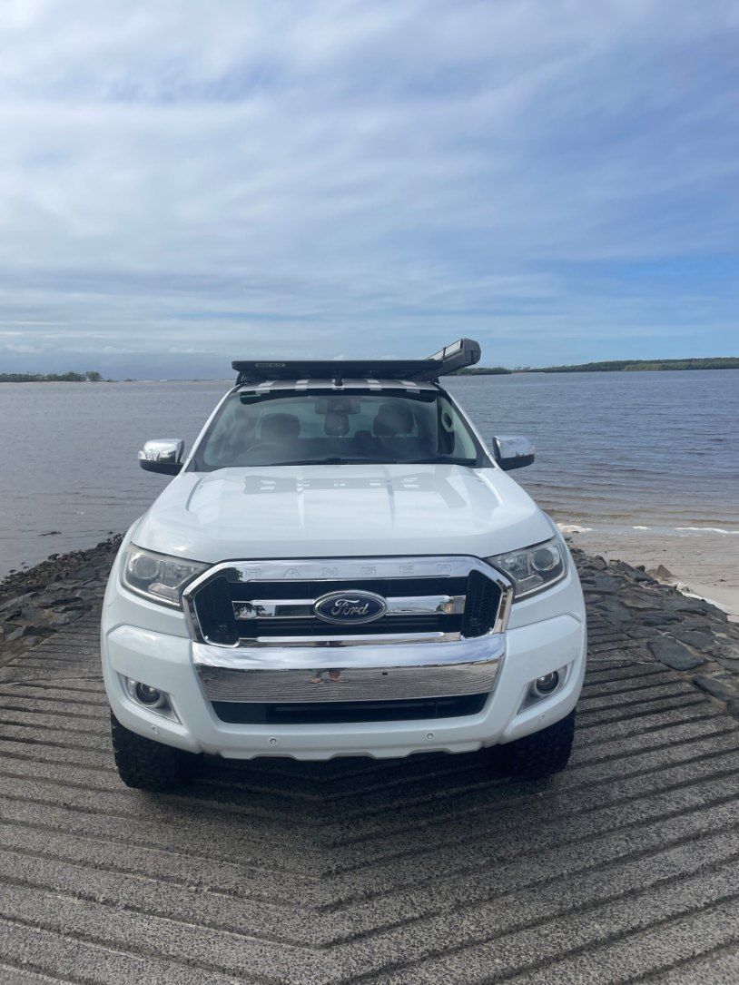 A White Ford Ranger is Parked on a Sandy Beach Next to a Body of Water β Pelican Motors Service Centre In Caloundra West, QLD