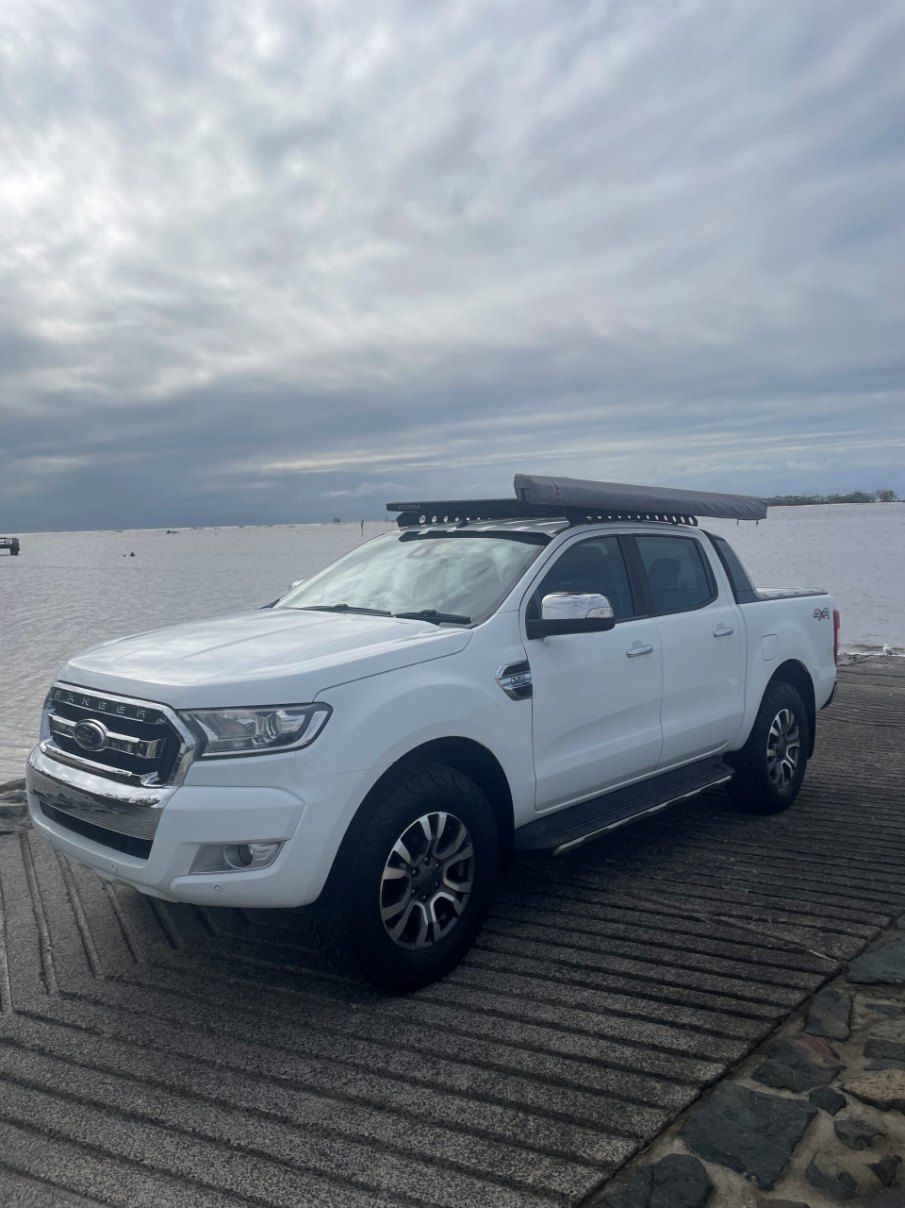 A White Truck With a Canopy on Top of It is Parked Next to a Body of Water β Pelican Motors Service Centre In Caloundra West, QLD