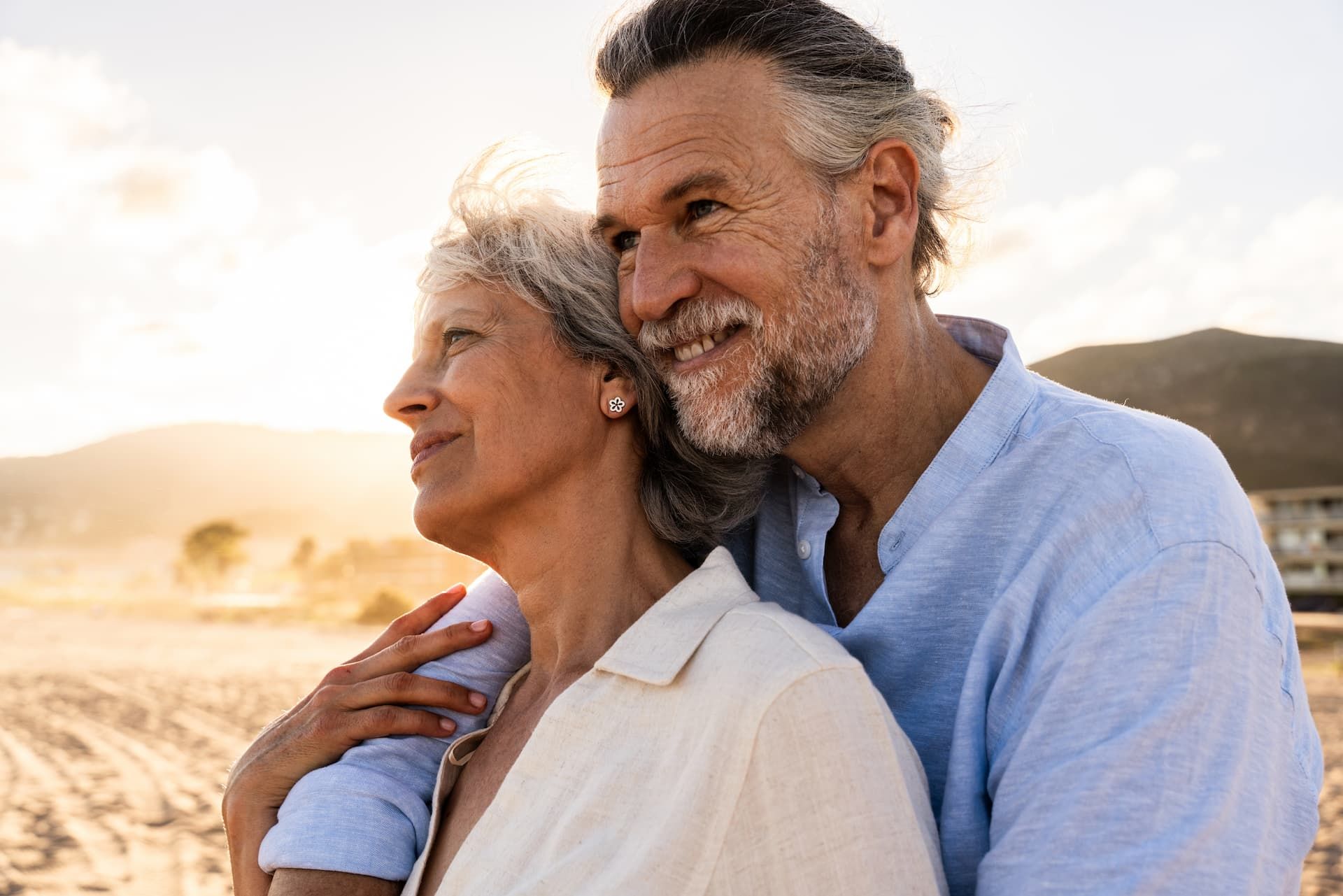 Smiling couple embracing outdoors by the beach at sunset
