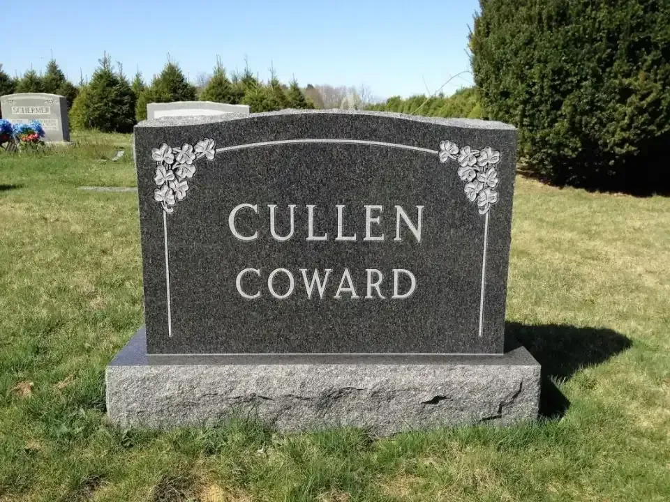 Gravestone reading “CULLEN COWARD” on a grassy cemetery lawn under a blue sky