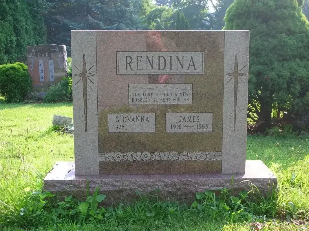 Stone memorial plaque reading “RENDINA” in a grassy cemetery setting