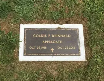 Gravestone plaque with gold lettering on white stone in grass, reading Goldie P. Reinhard Applegate