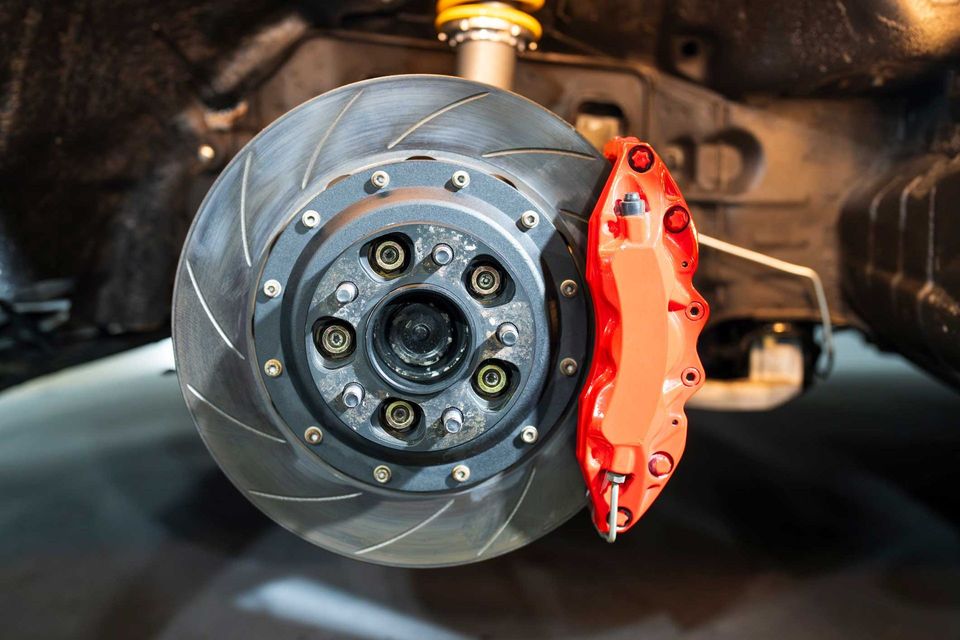 A close up of a brake disc on a car with a red brake caliper.