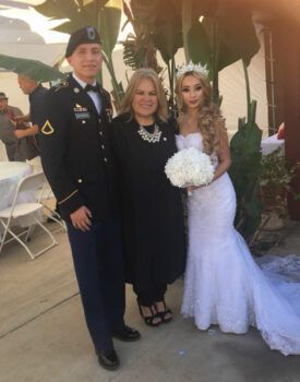 A man in a military uniform is posing for a picture with a bride and groom.