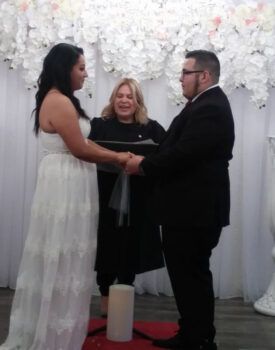 A bride and groom are holding hands during their wedding ceremony.