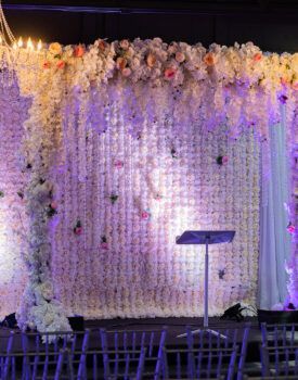 A stage decorated with white flowers and purple lights.