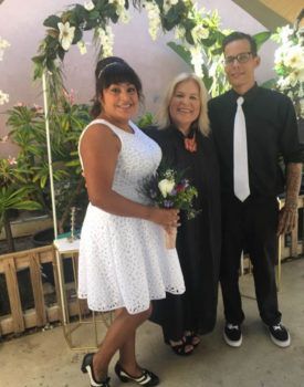 A woman in a white dress is standing next to a man and woman