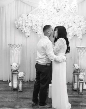 A black and white photo of a bride and groom kissing at their wedding ceremony.