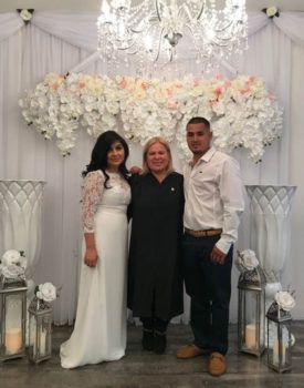 A bride and groom are posing for a picture with a wedding planner.