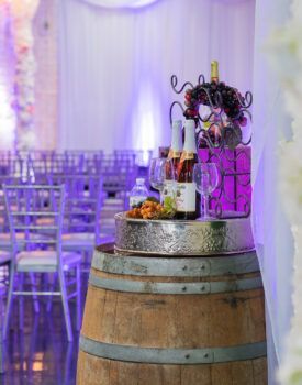A wooden barrel filled with wine bottles and glasses.