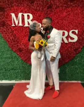 A bride and groom kissing in front of a wall that says mr and mrs