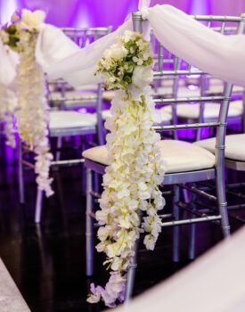A row of chairs decorated with white flowers for a wedding ceremony.