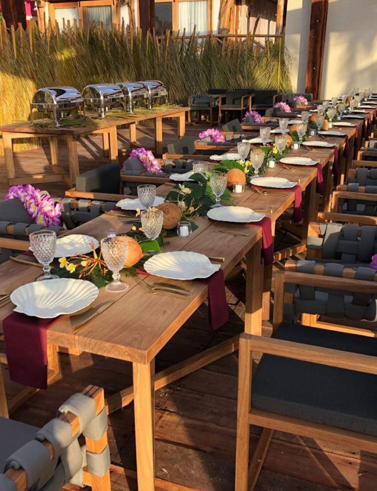 Long outdoor dinner table set with floral decorations and serving stations.