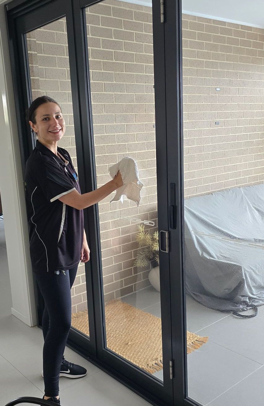 A cleaner is wiping down inside window of home — A Place 2 Shine In Chisholm, NSW