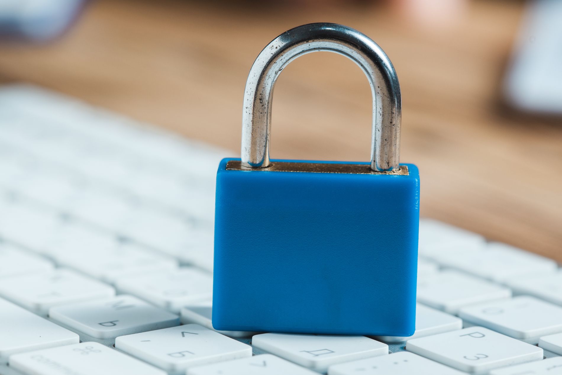 Lucchetto blu su una tastiera bianca, simbolo di sicurezza dei dati e di sicurezza su Internet.
