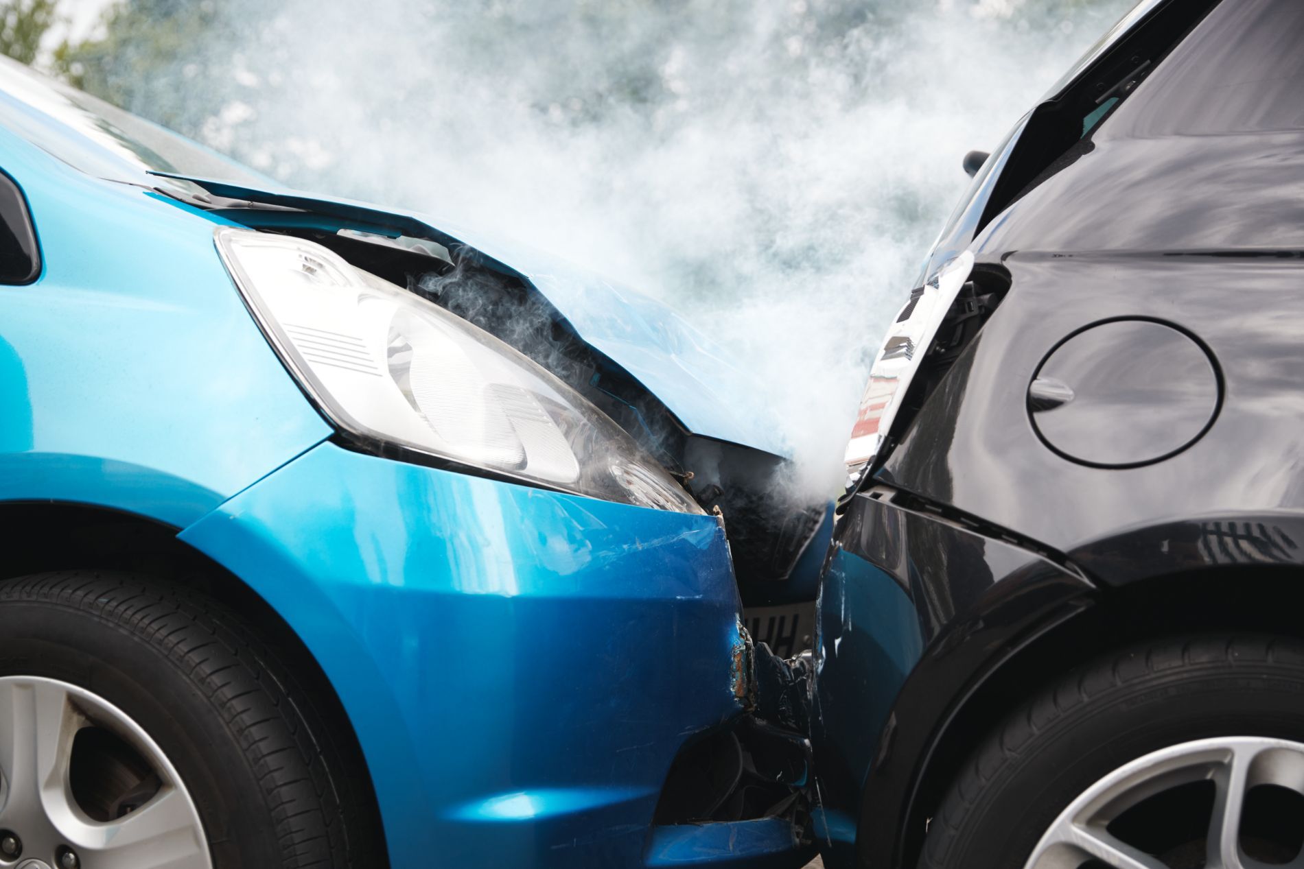 Due auto, una blu e una nera, si sono scontrate frontalmente. Dal cofano dell'auto blu si alza del fumo.