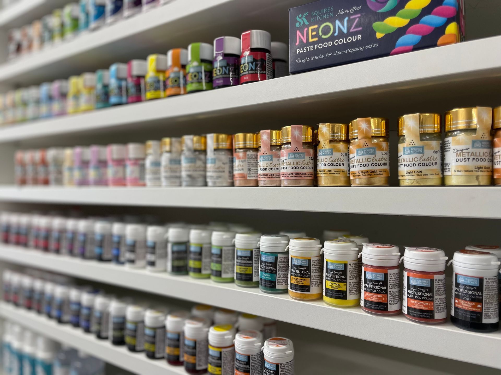 A shelf filled with lots of bottles of paint.