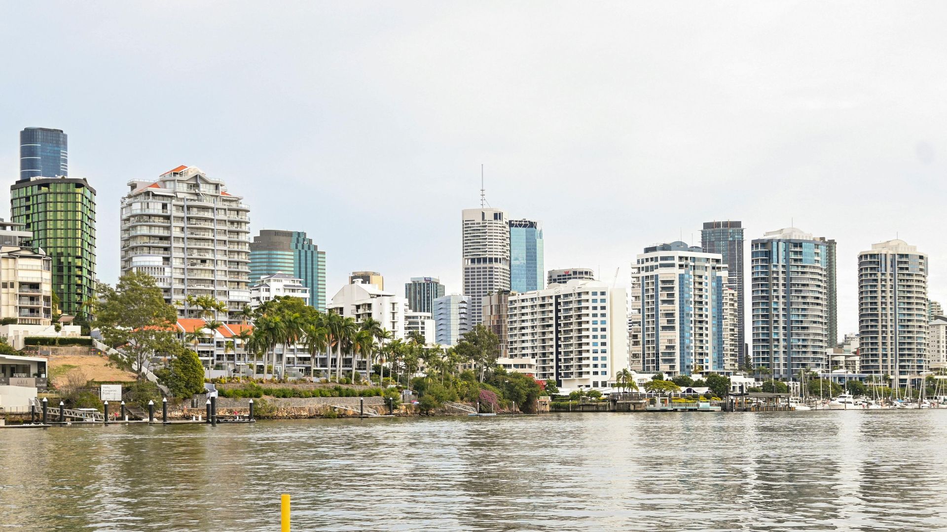 City skyline of tall modern buildings along a waterfront under a bright sky