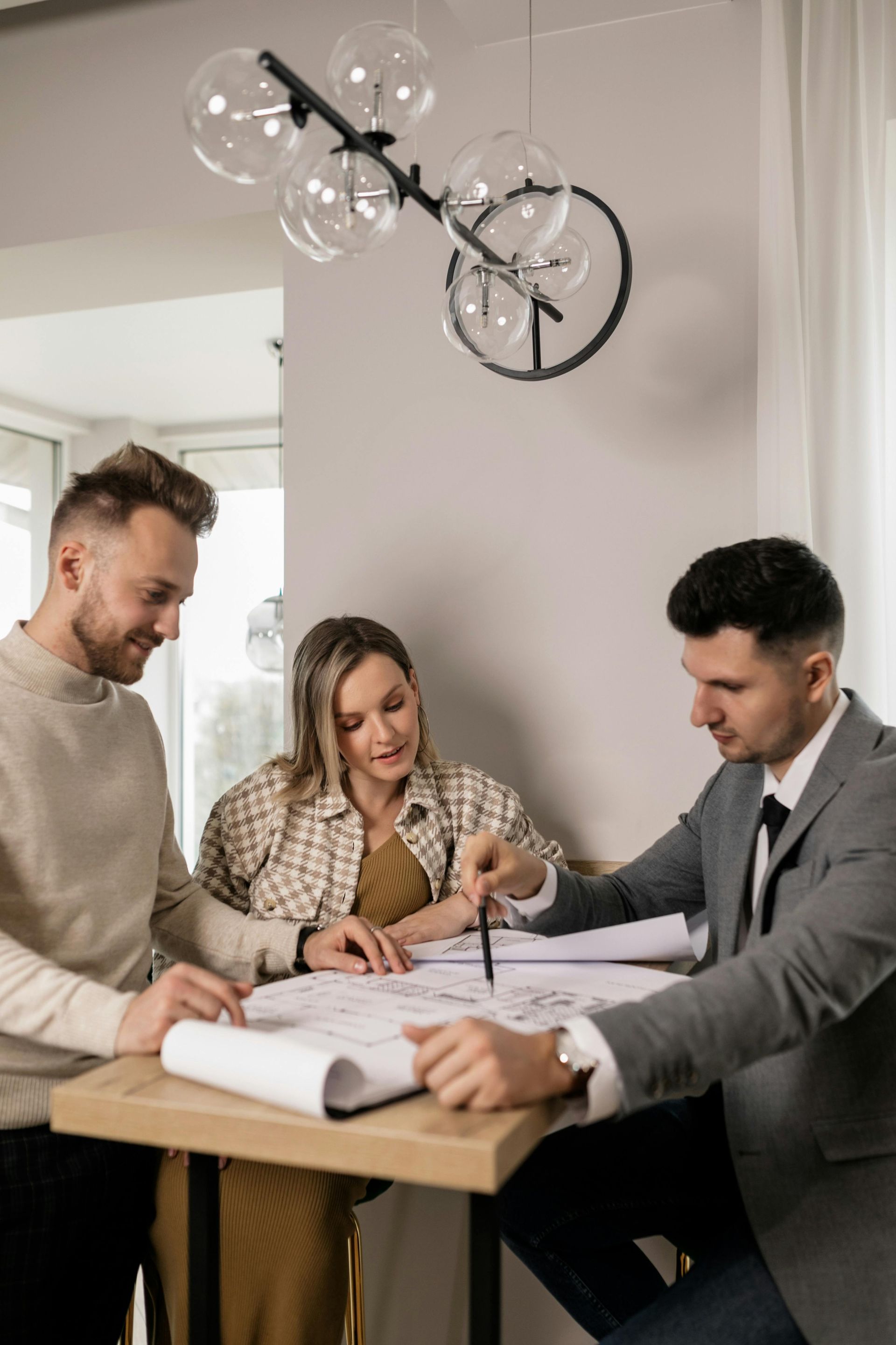 Three colleagues reviewing documents at a table in a bright office