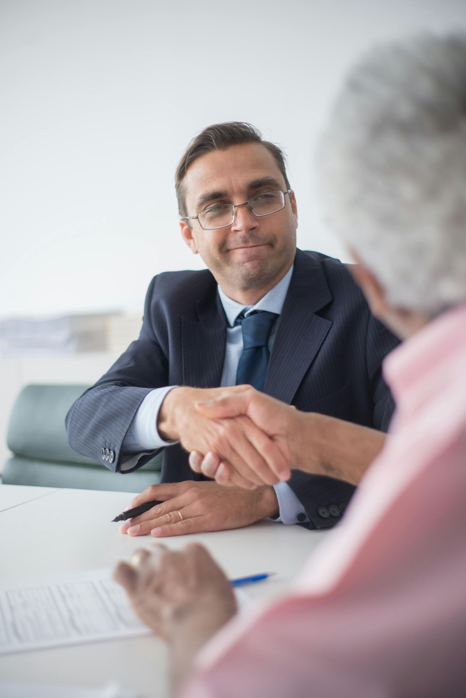 Business meeting with two people shaking hands across a conference table.
