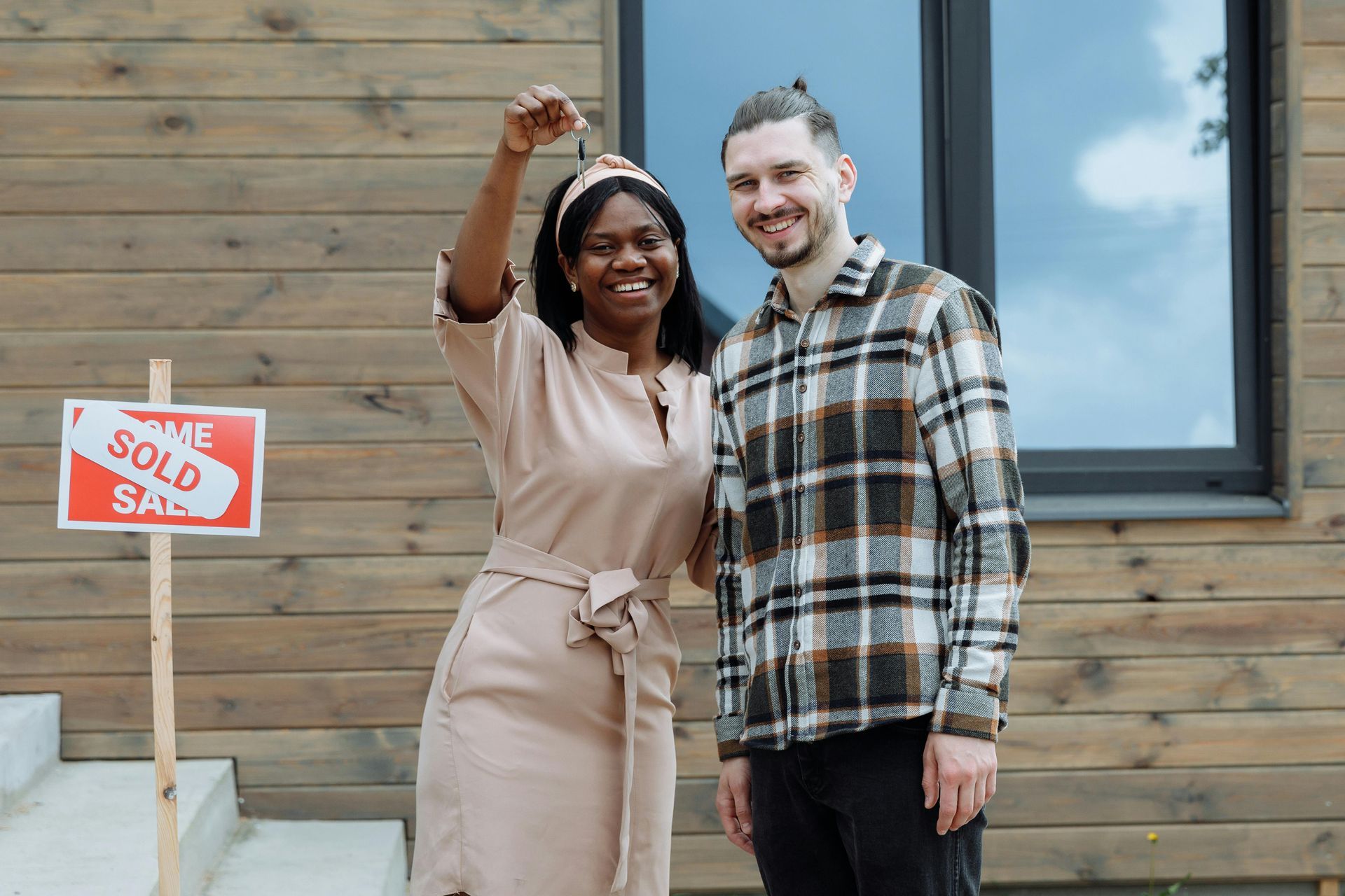 Happy couple standing outside a wooden house with a red 