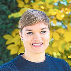Porträtfoto von Anika Reichwald, Jurorin 2024 und Kuratorin, mit kurzem blondem Haar vor gelbem Laubhintergrund.