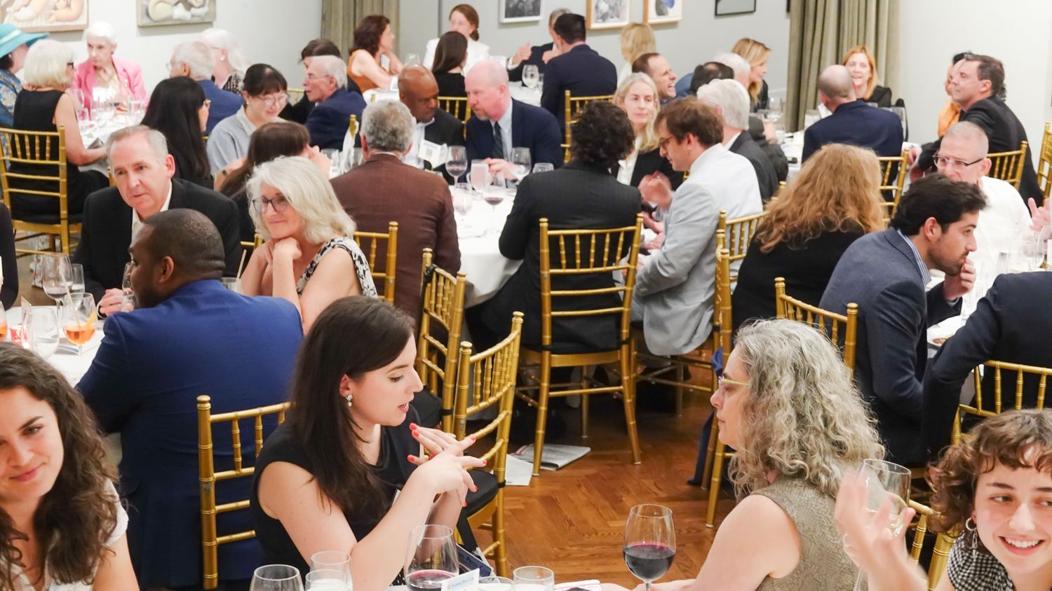 People seated at tables in a room, presumably a banquet or reception.
