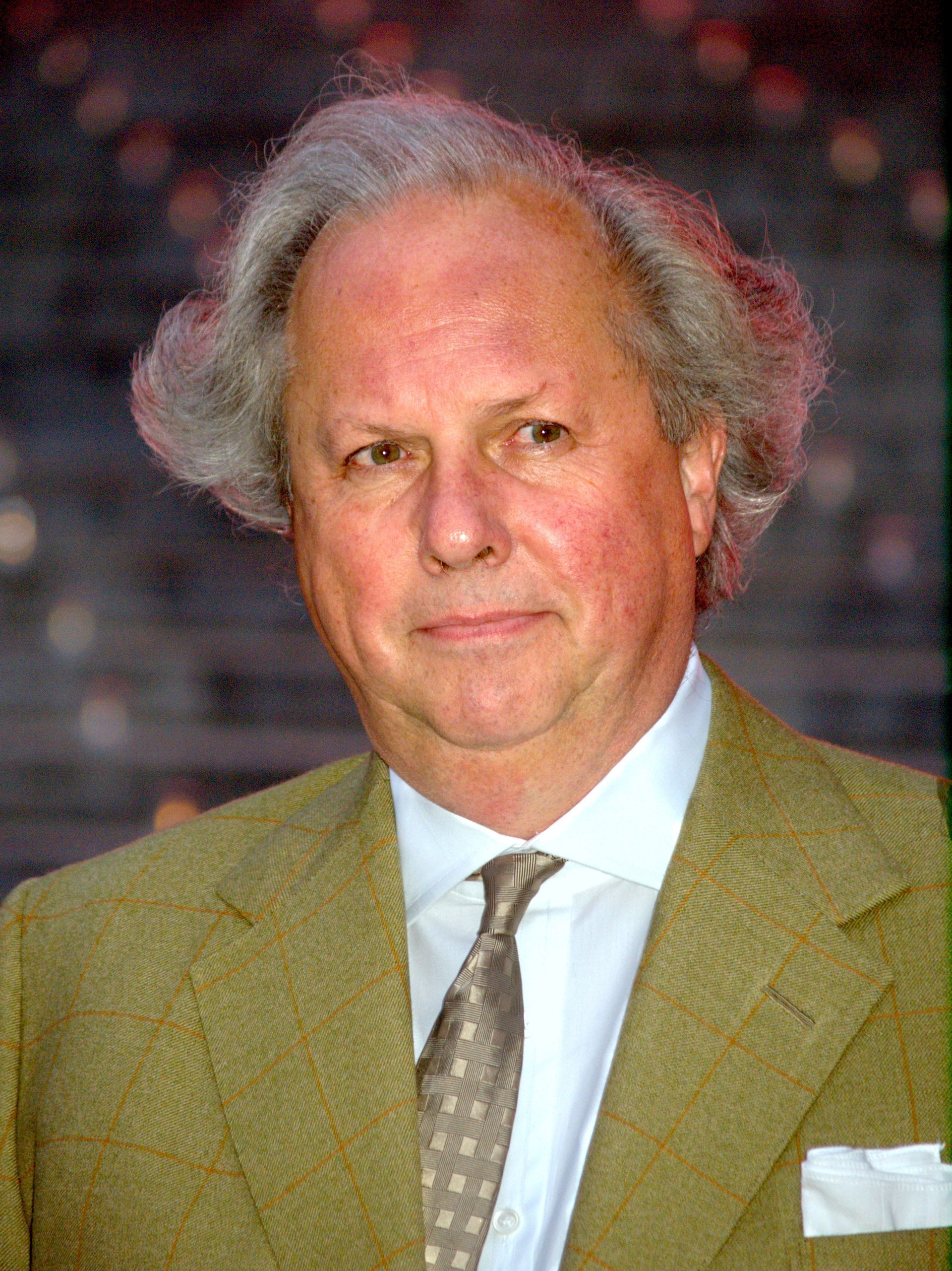 Portrait of a man in a tan suit and tie against a blurred background