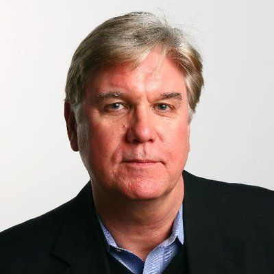 Man with fair skin, in dark jacket and blue shirt, looking at camera.
