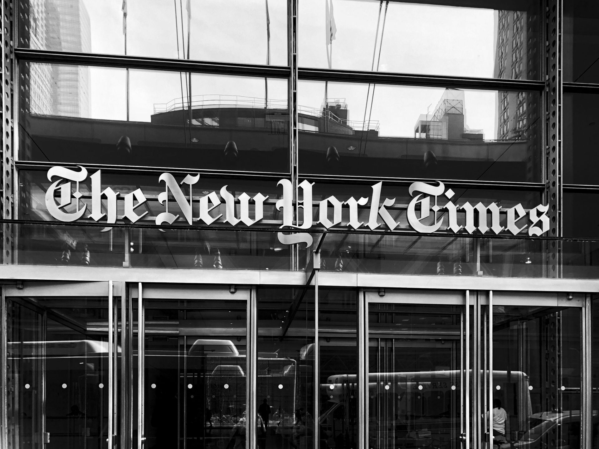 The New York Times sign above a glass-fronted building entrance