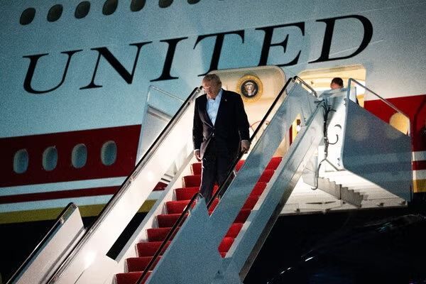 Man descending airplane stairs beside a United jet, with red-carpeted steps and United logo visible