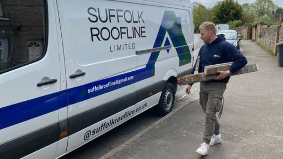 Darren Frost, Director of Suffolk Roofline carrying something to a signwritten van.