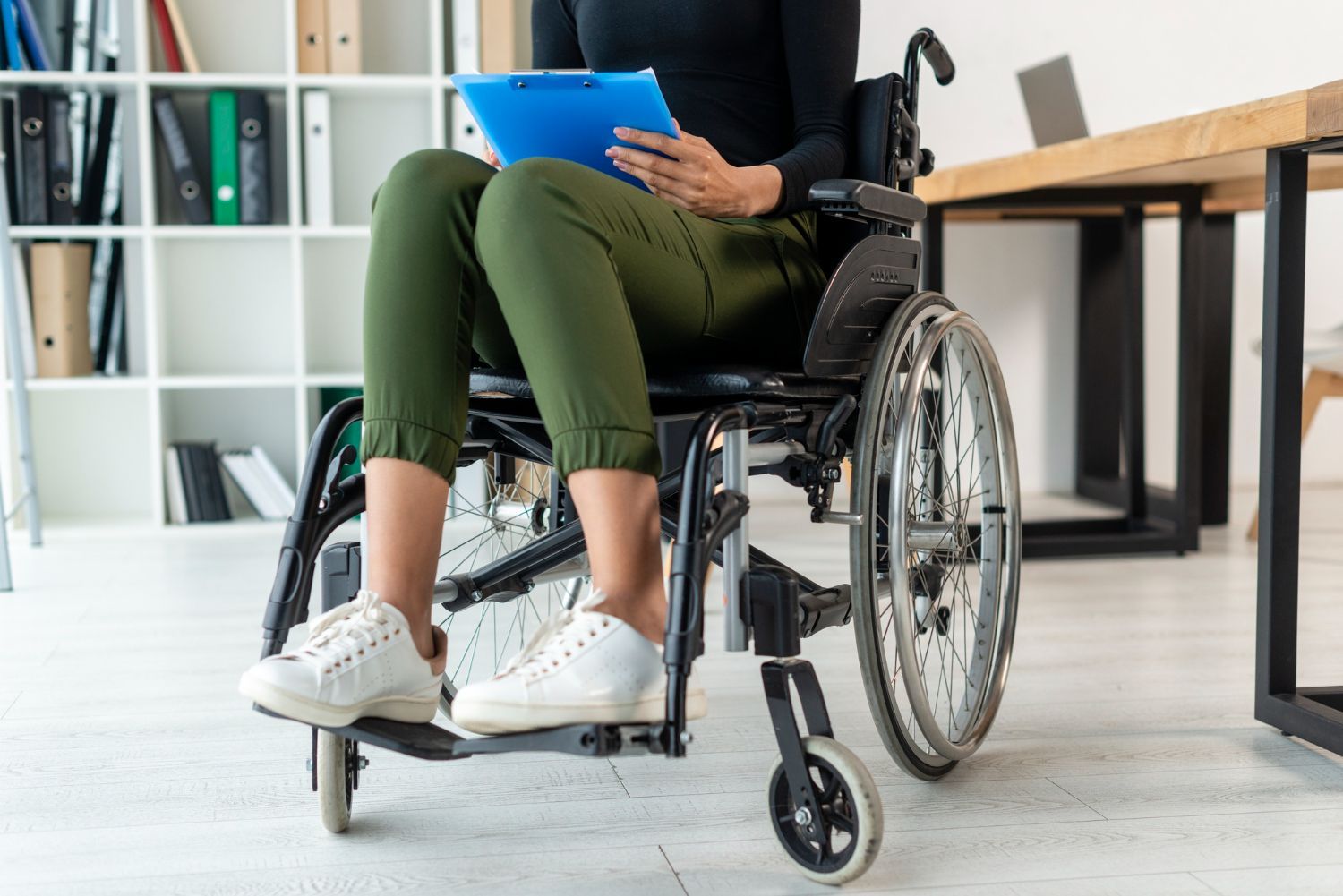 Person in a wheelchair using a blue tablet in a bright office setting