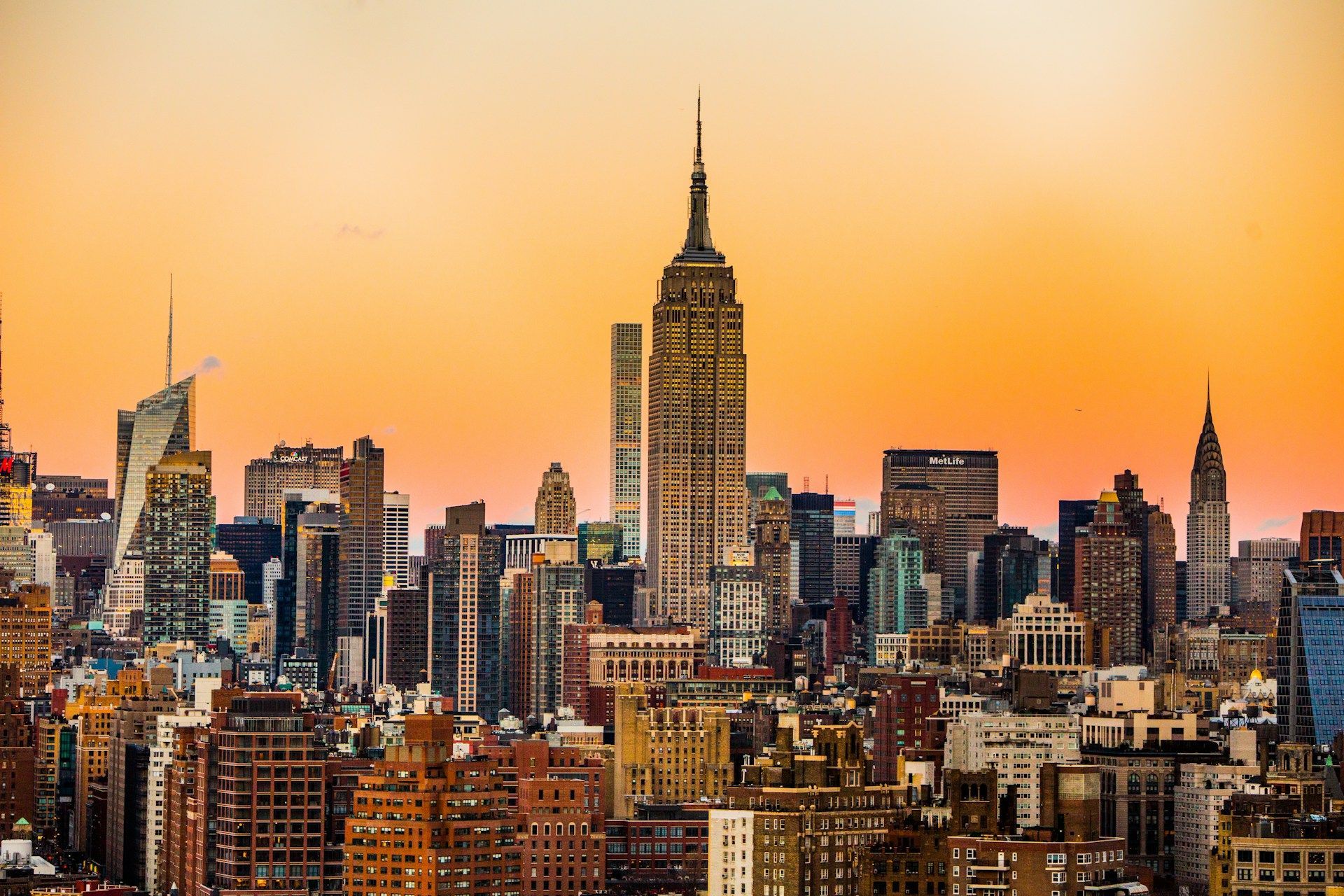 New York City skyline at sunset with the Empire State Building centered against an orange sky